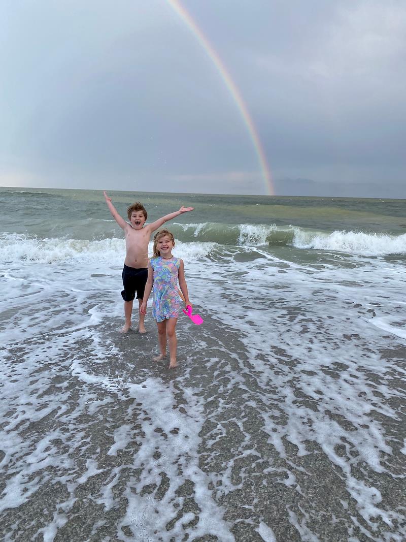 kids smiling on beach with rainbow