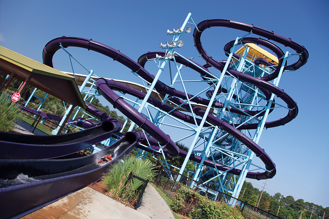 A large outdoor water park with purple water slides and a blue metal framework.